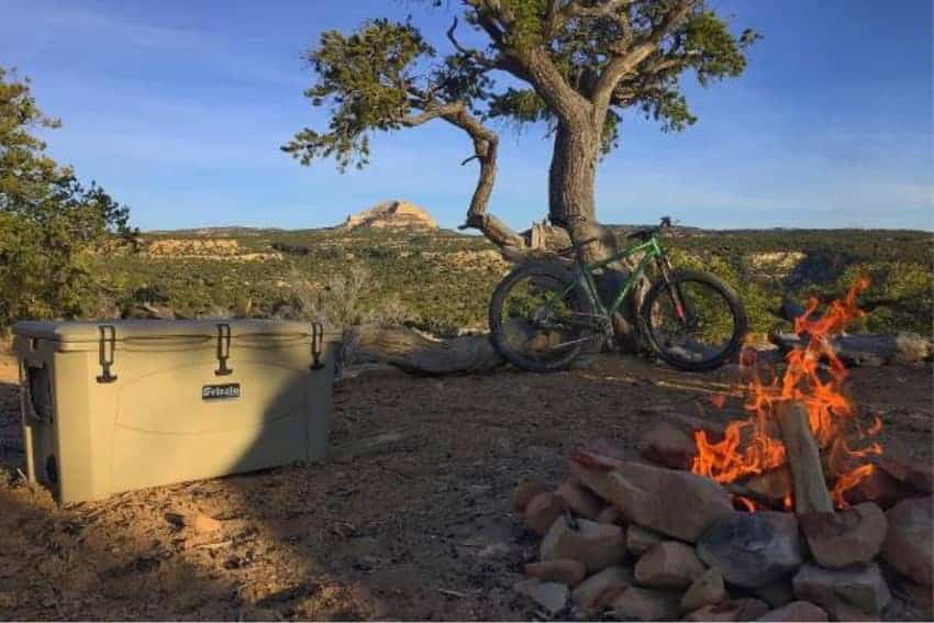 grizzly 100 quart cooler next to a campfire during sundown