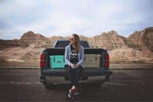 how to plan a road trip, women sitting on tailgate of pickup truck with two 20 quart rotomolded coolers
