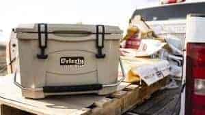 american farmer using a tan grizzly 20 cooler sitting on pallet in back of truck surrounded by corn seed bags