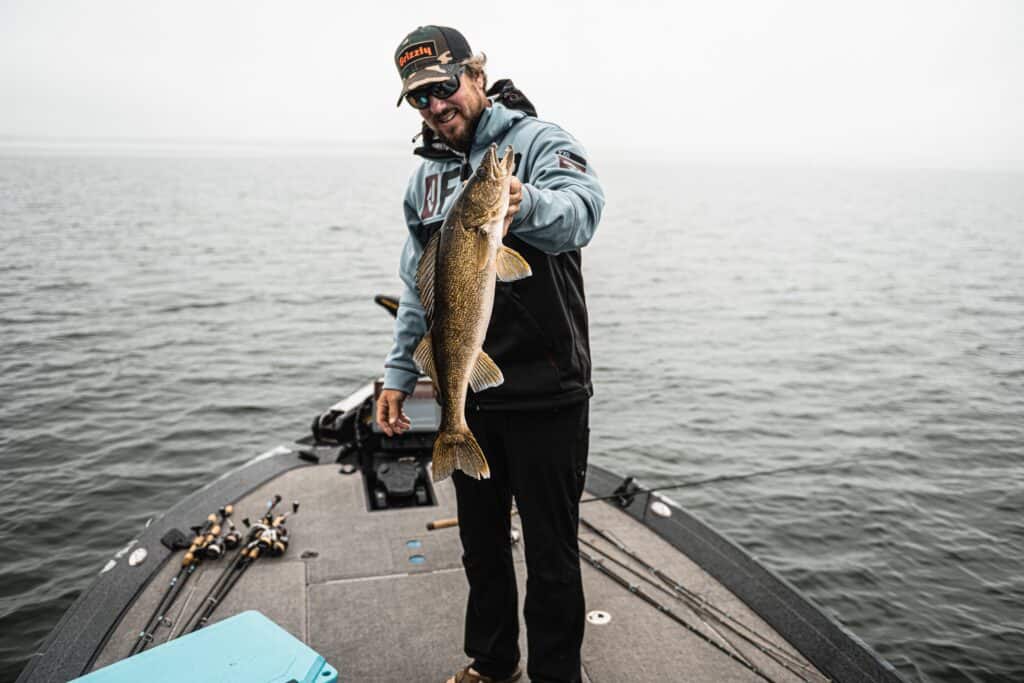 Matt Peters holding a recently caught Walleye on bow of boat. 