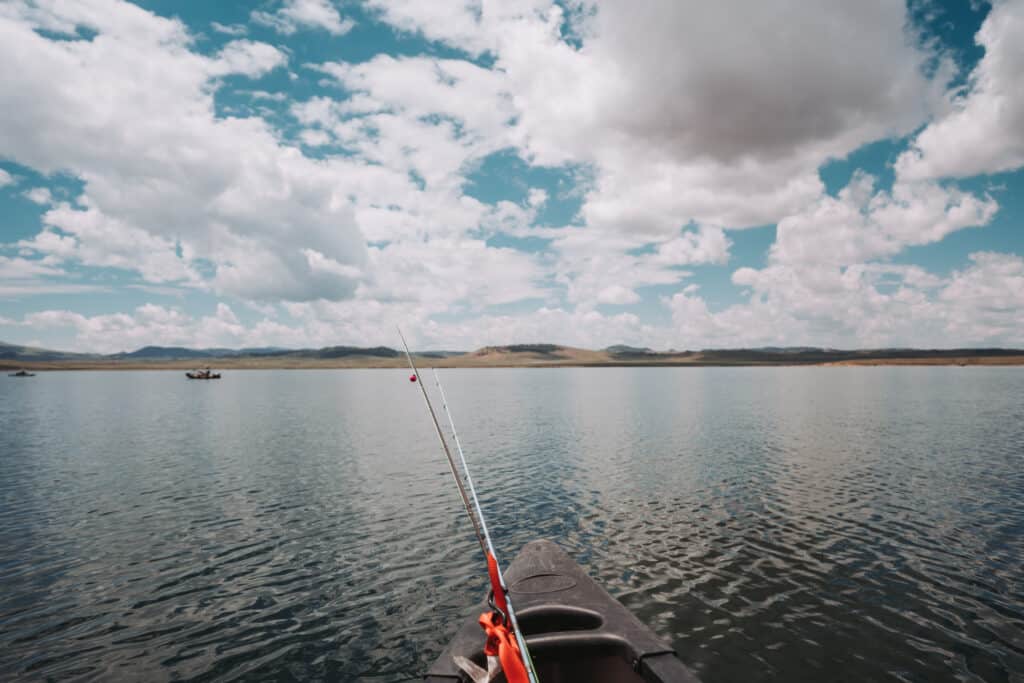 mental health benefits of fishing, bow of kayak with fishing gear and landscape image of open water