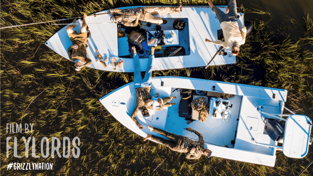 Aerial View Of Two Boats In Tall Grass With People Laying On Boats